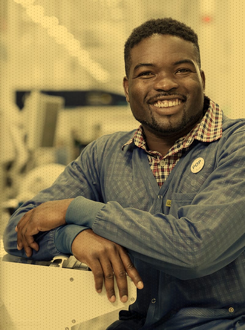 Man sitting by machine smiling at camera