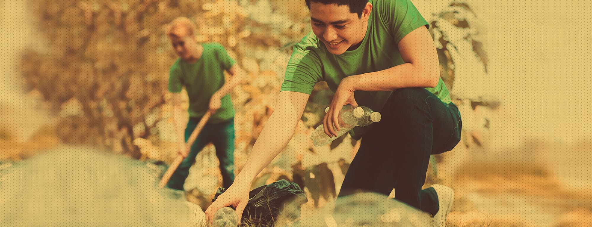 Male, kneeling, picking up trash and recycling in park and disposing of it properly