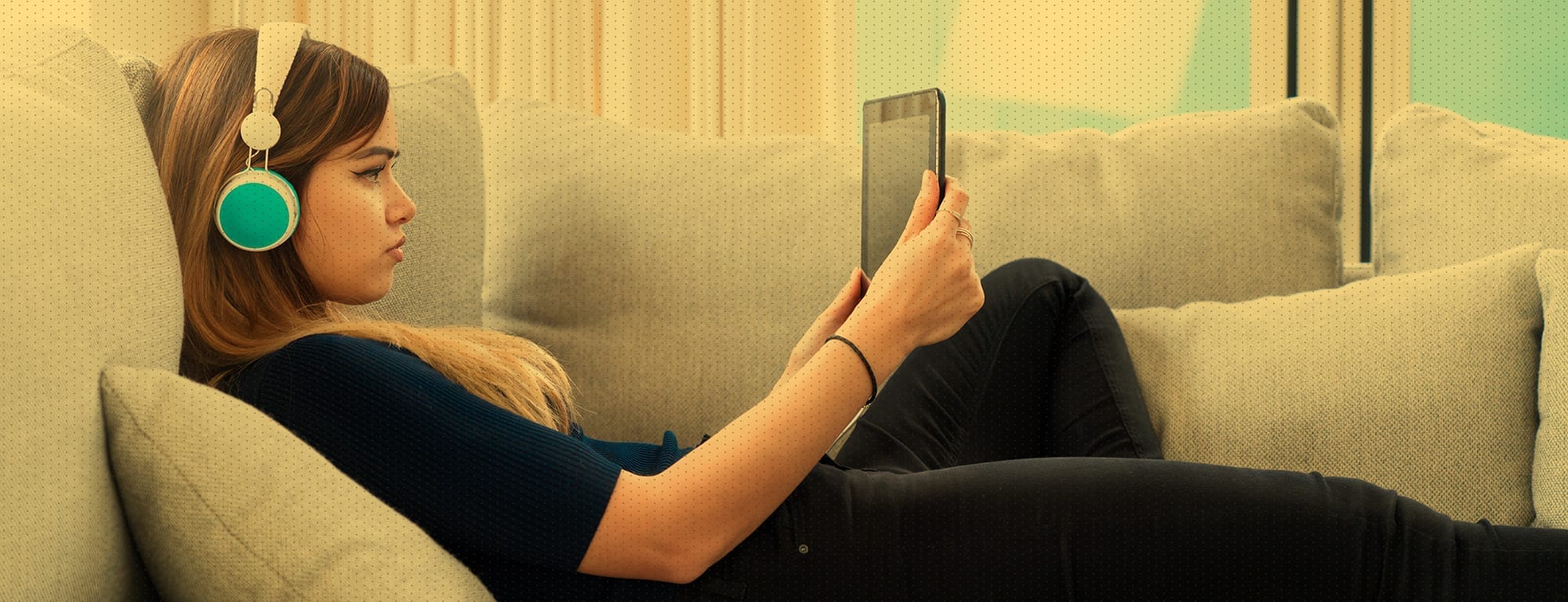 Women on couch wearing headphones looking at tablet