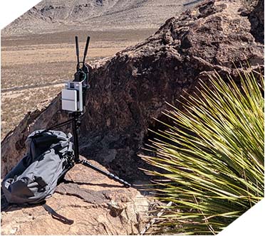 An Echodyne EchoGuard radar unit mounted on a tripod in a rugged, desert environment.