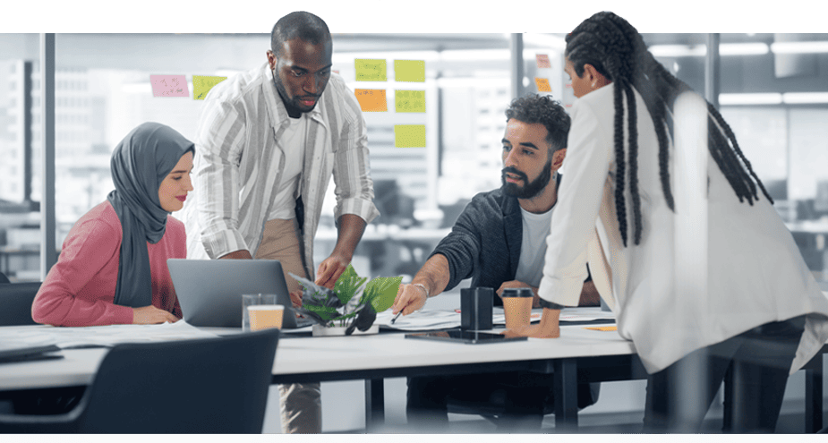 Four employees around a table looking at documents and plans