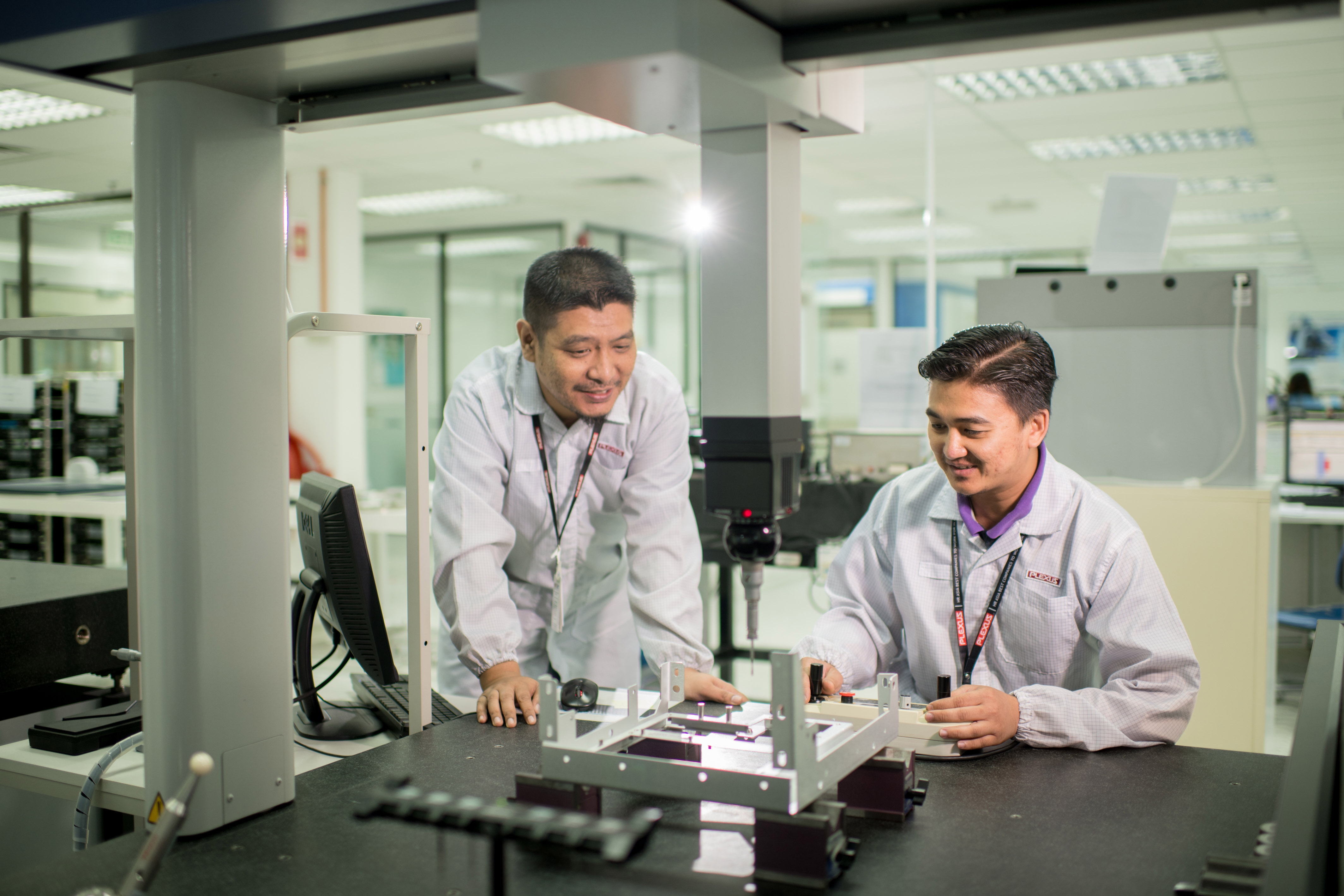 Two Plexus engineers working in a Failure Analysis Lab to inspect a complex assembly for precision and quality control.