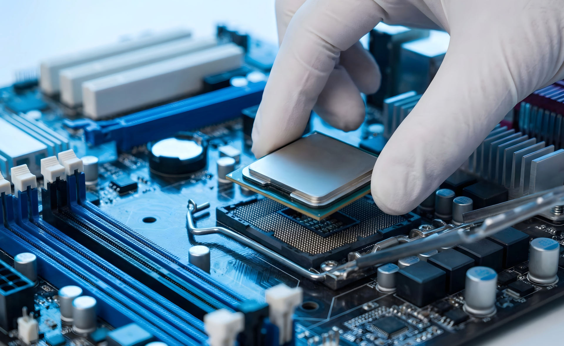 A close-up shot of a hand wearing a white glove carefully inserting a square CPU processor chip into its dedicated socket on a blue computer.
