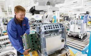 A member of the Plexus team carefully removing an internal printed circuit board assembly from a medical ultrasound machine.